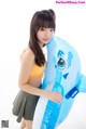 A young woman holding an inflatable dolphin in her hands.