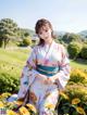 A woman in a kimono sitting in a field of flowers.