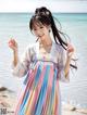 A woman in a colorful dress standing on a beach.