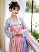 A woman in a pink and blue hanbok is holding a cell phone.