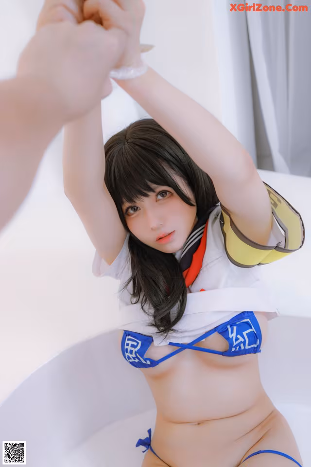 A woman in a blue bikini sitting in a bathtub.