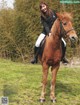 A woman riding on the back of a brown horse.