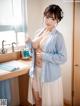 A woman in a blue kimono standing in a kitchen.