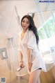 A woman in a white shirt is standing in a shower.