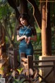 A woman in a blue dress standing on a wooden bridge.