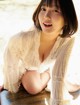 A woman in a white blouse sitting on a wooden table.