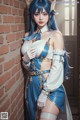 A woman in a blue and white outfit leaning against a brick wall.