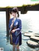 A woman in a blue kimono standing in the water.