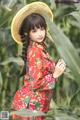 A woman in a red dress and a straw hat posing for a picture.