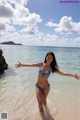 A woman in a blue bikini standing in the ocean.