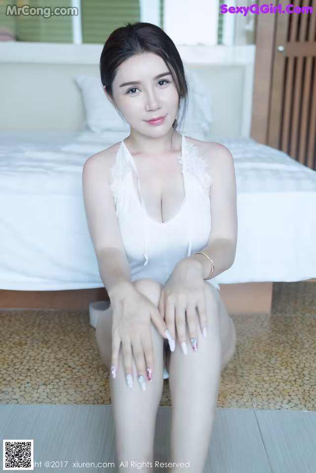 A woman sitting on the floor in a white lingerie.