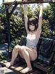 A woman sitting on a wooden bench in a park.