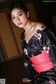 A woman in a black and pink kimono posing for a picture.