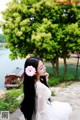 A woman in a white dress with a pink flower in her hair.