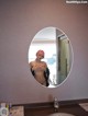 A woman with pink hair standing in front of a mirror.